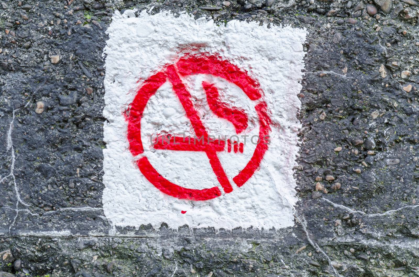 Graffiti smoking ban on an old concrete wall.