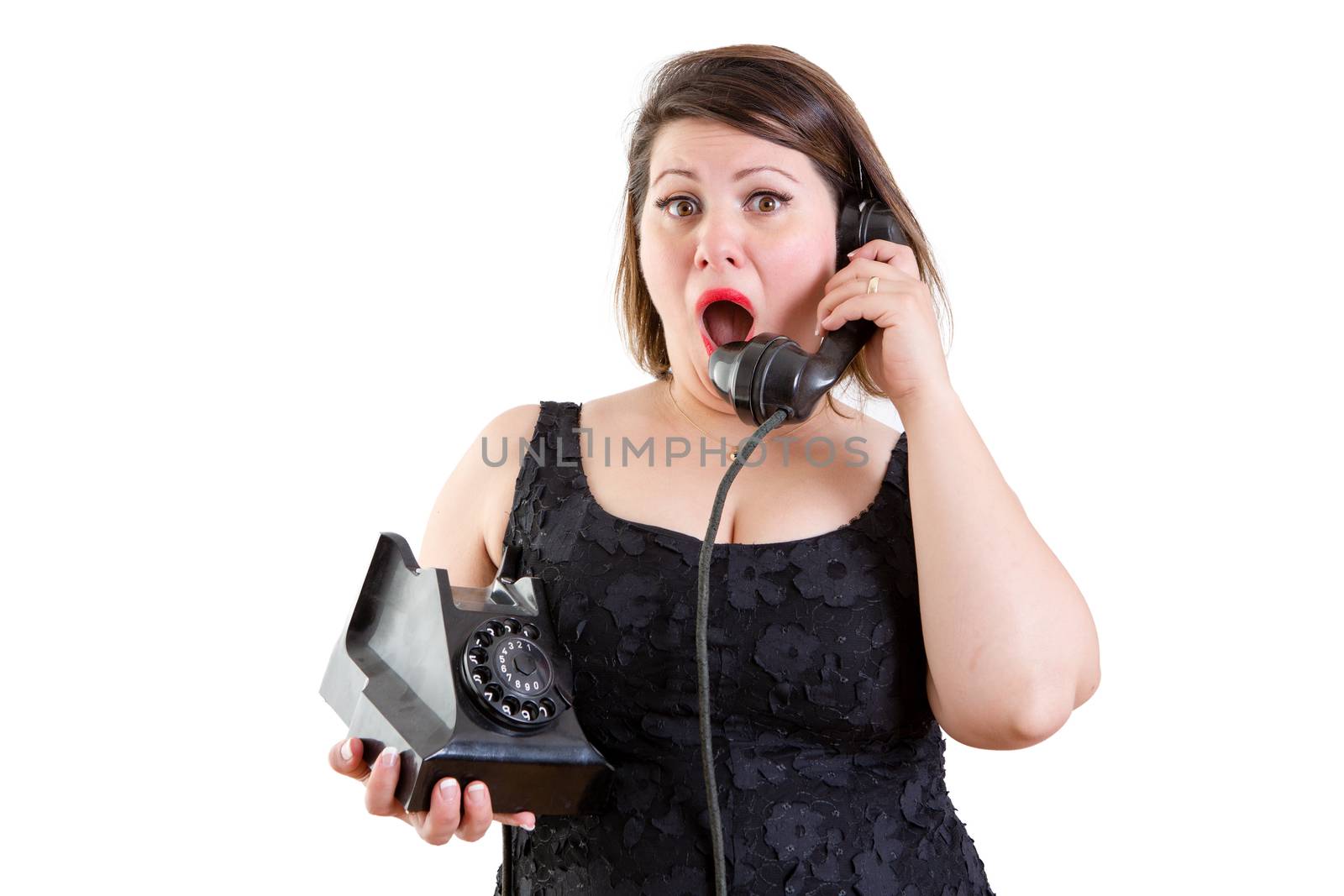 Astonished woman talking on an old fashioned rotary telephone reacting to surprising news in a communications concept on white