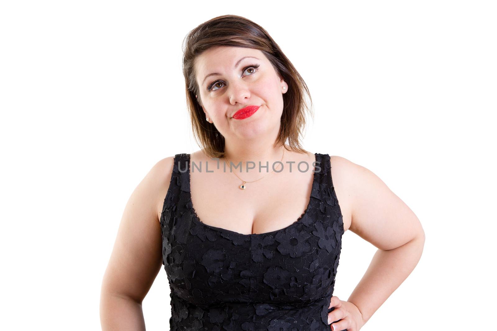 Pensive woman standing thinking looking up into the air with her hand on her hip and a serious expression, isolated on white