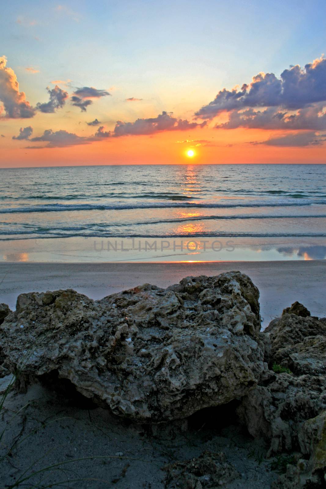 A sunset over the ocean with rocks