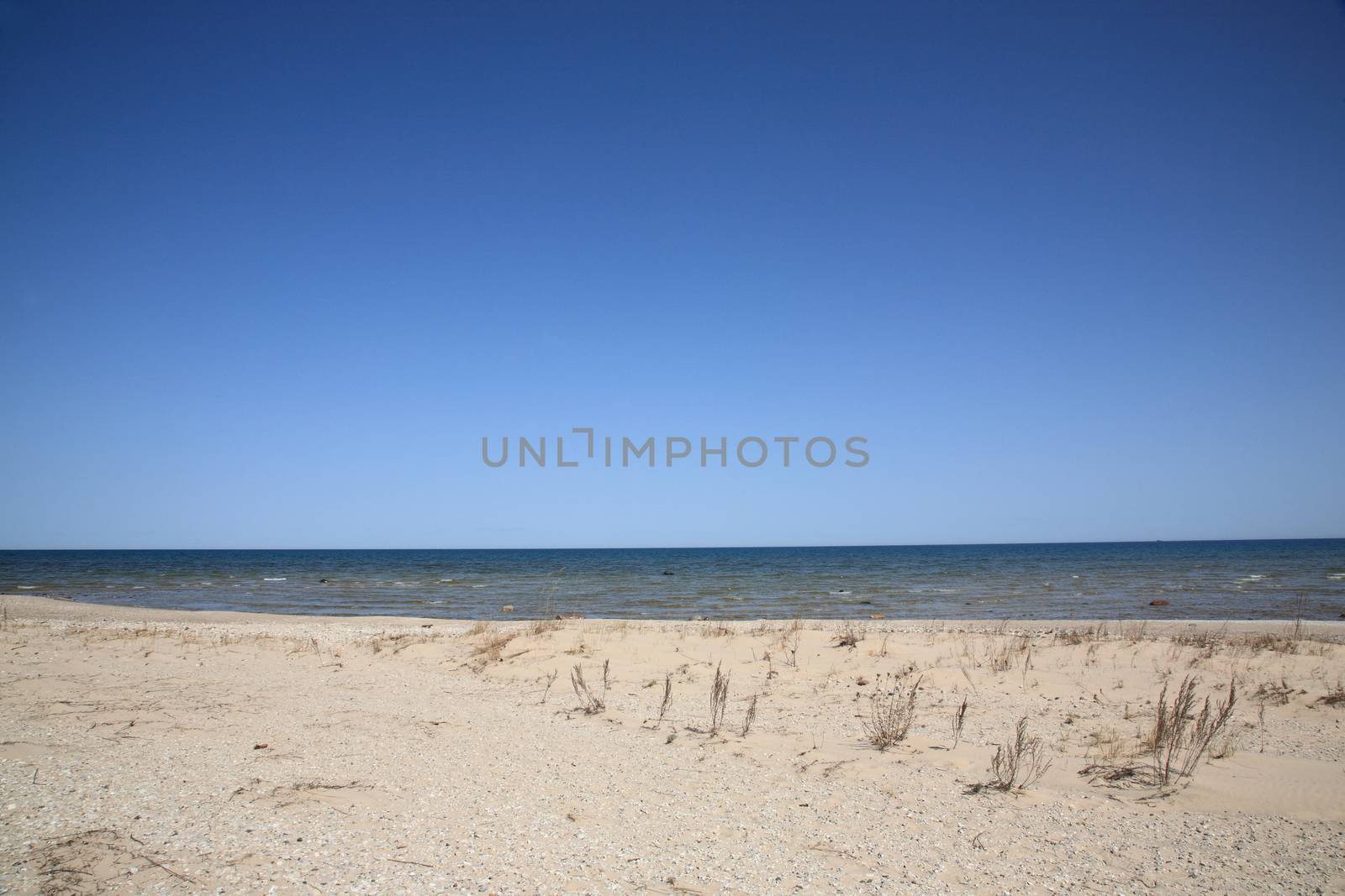 Waves reach long sandy shoreline beach of Great Lake Huron in Michigan.