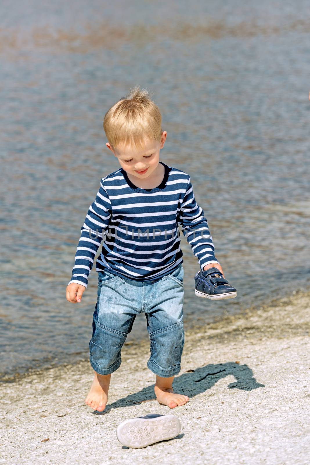 Little preschool boy playing on beach outdoors by Nanisimova