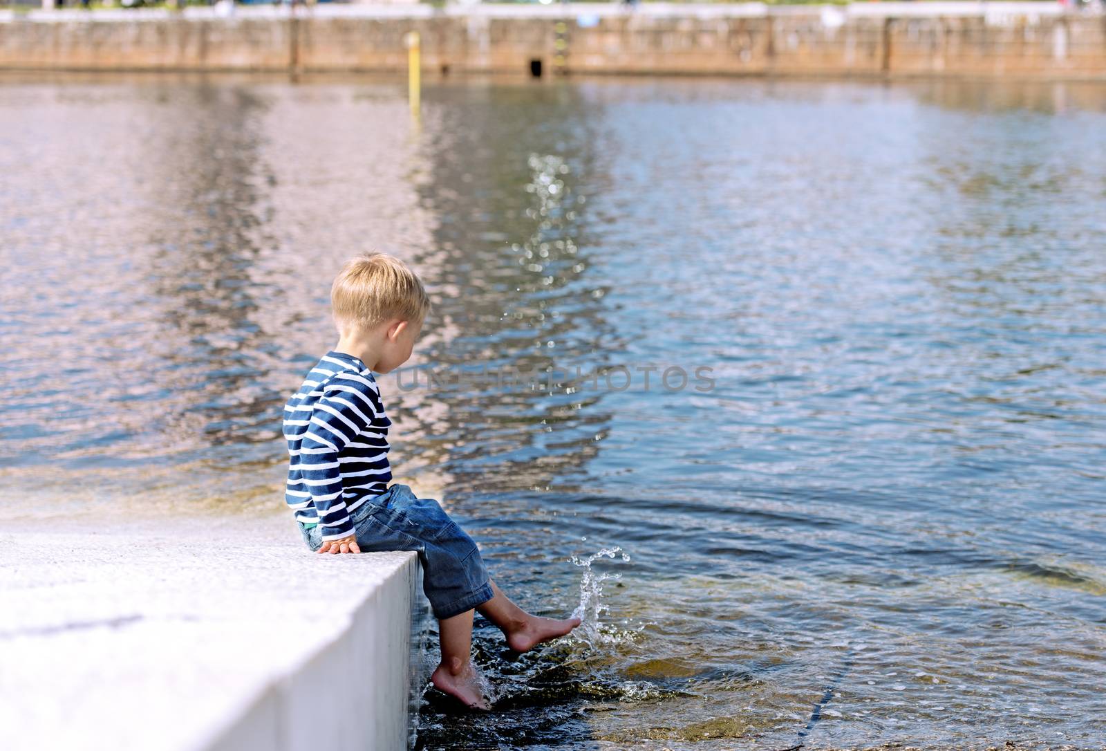 Little preschool boy playing on beach with water by Nanisimova