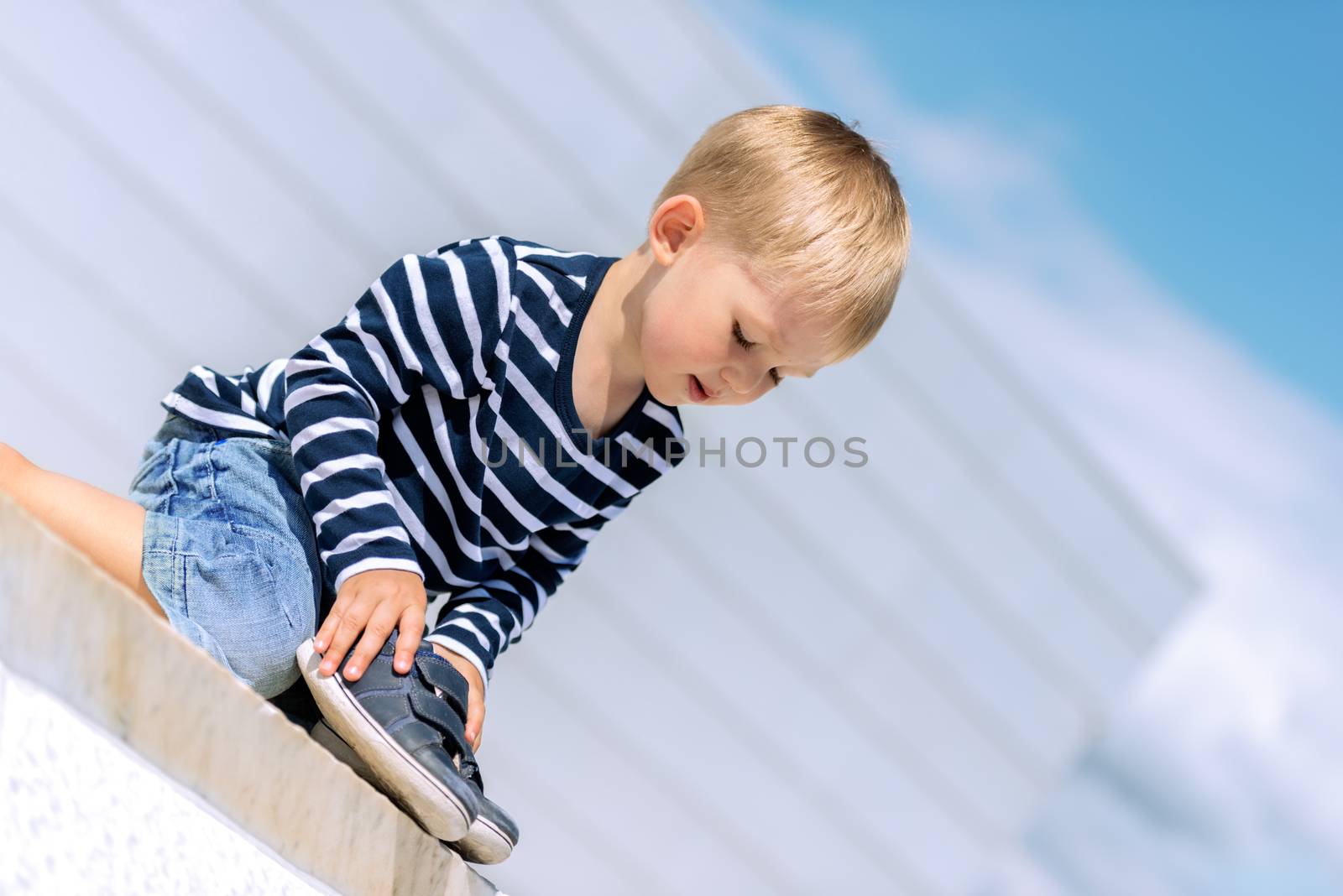 Portrait of little preschool boy outdoors with shoes by Nanisimova
