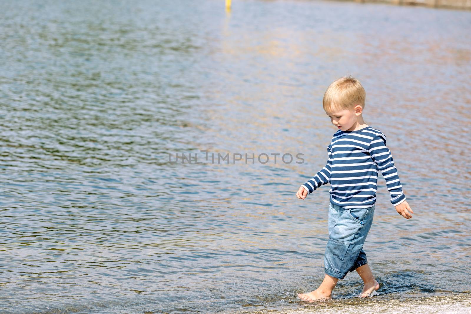 Little preschool boy walking on beach outdoors by Nanisimova