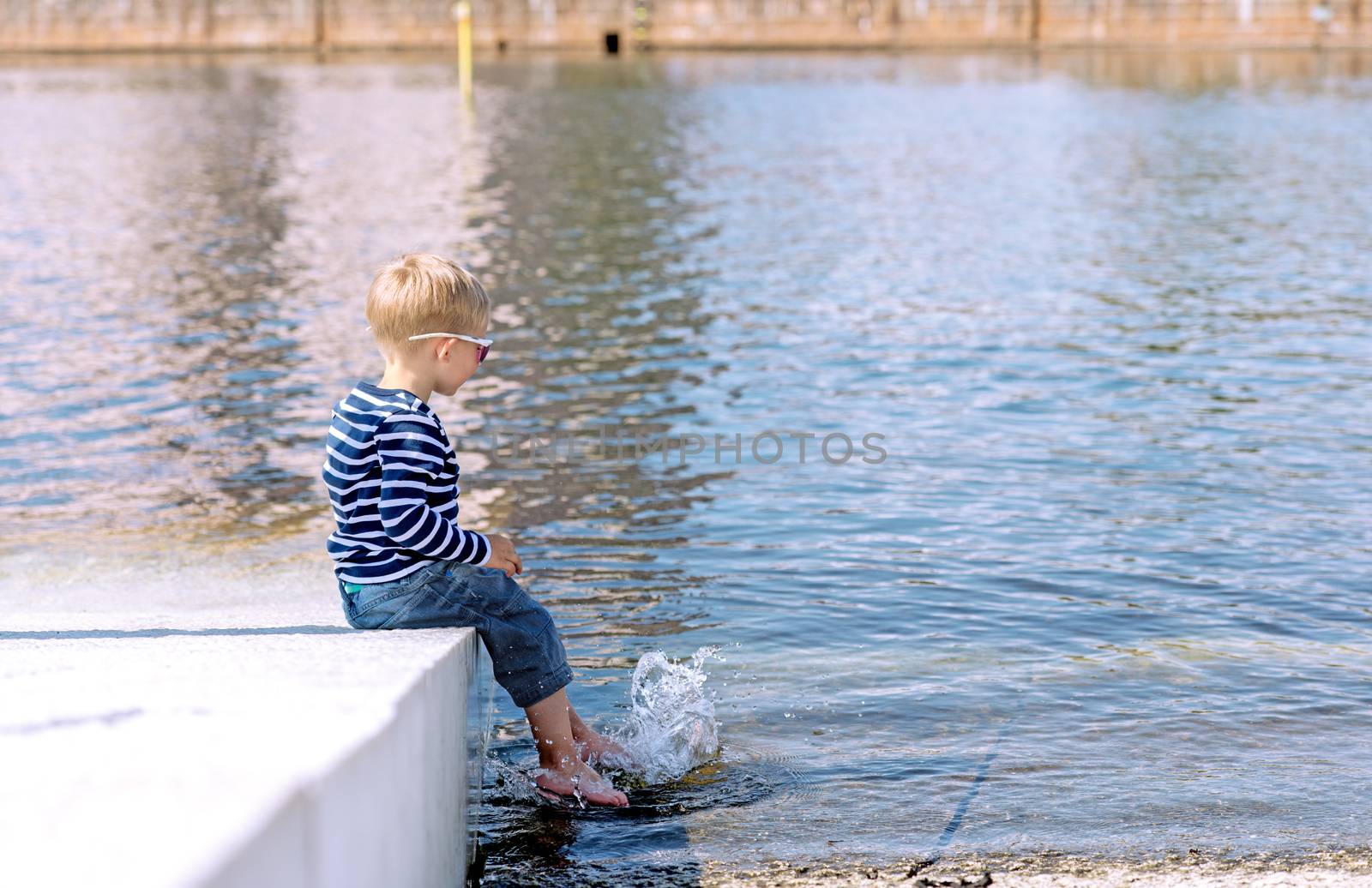 Little preschool boy playing on shore outdoors