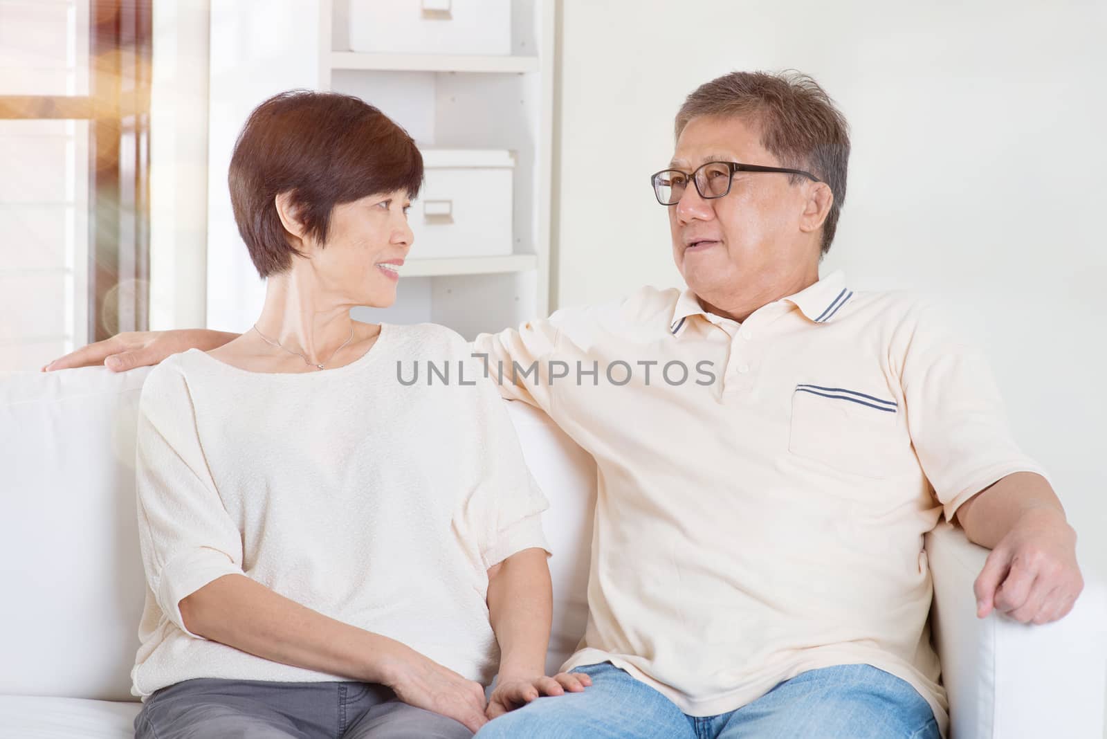 Senior couple having conversation, sitting on sofa at home. Living lifestyle of Asian family.