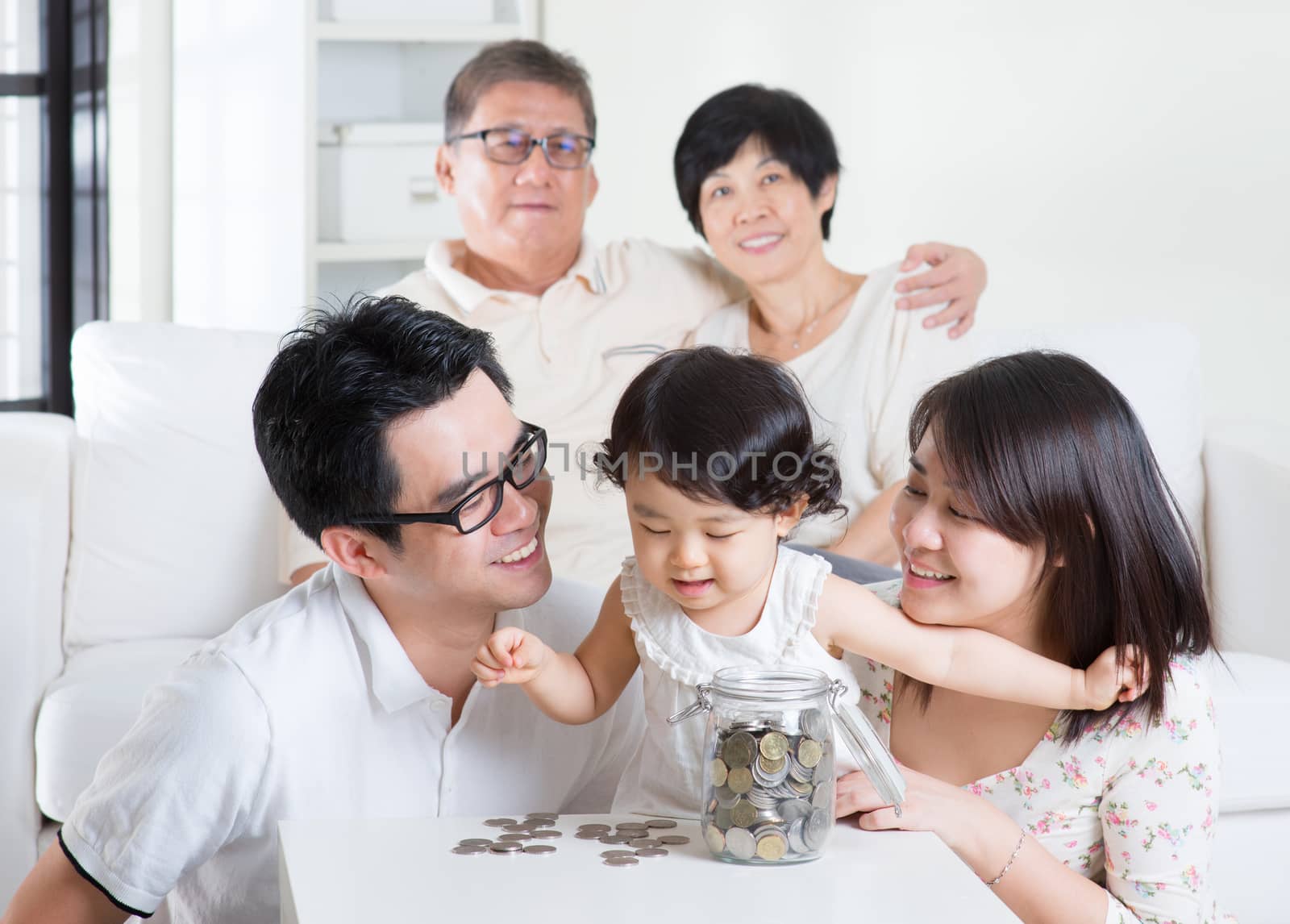 Toddler counting coins. Asian family money savings concept. Multi generations living lifestyle at home.