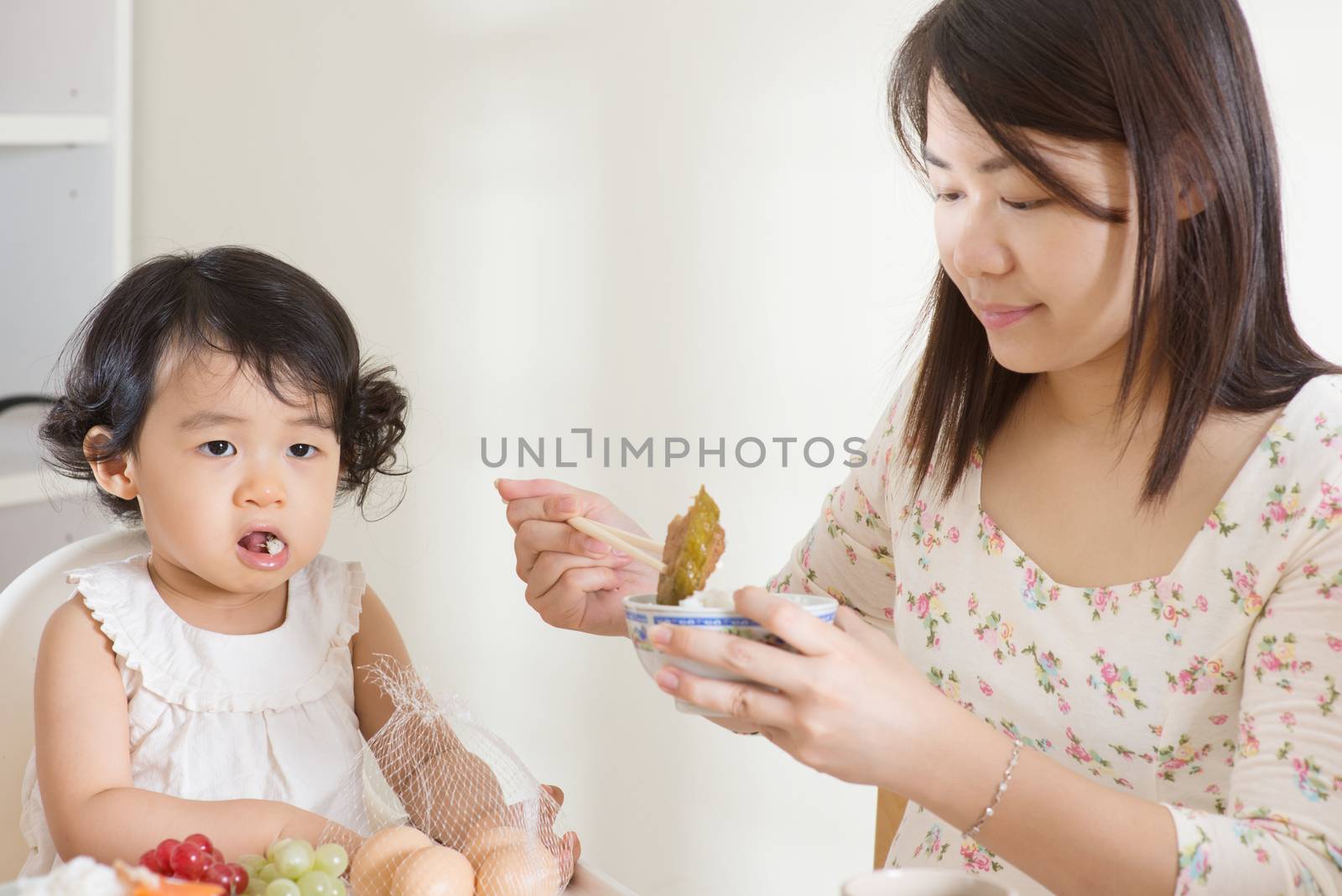 Asian mother feeding her child at home. Family living lifestyle.