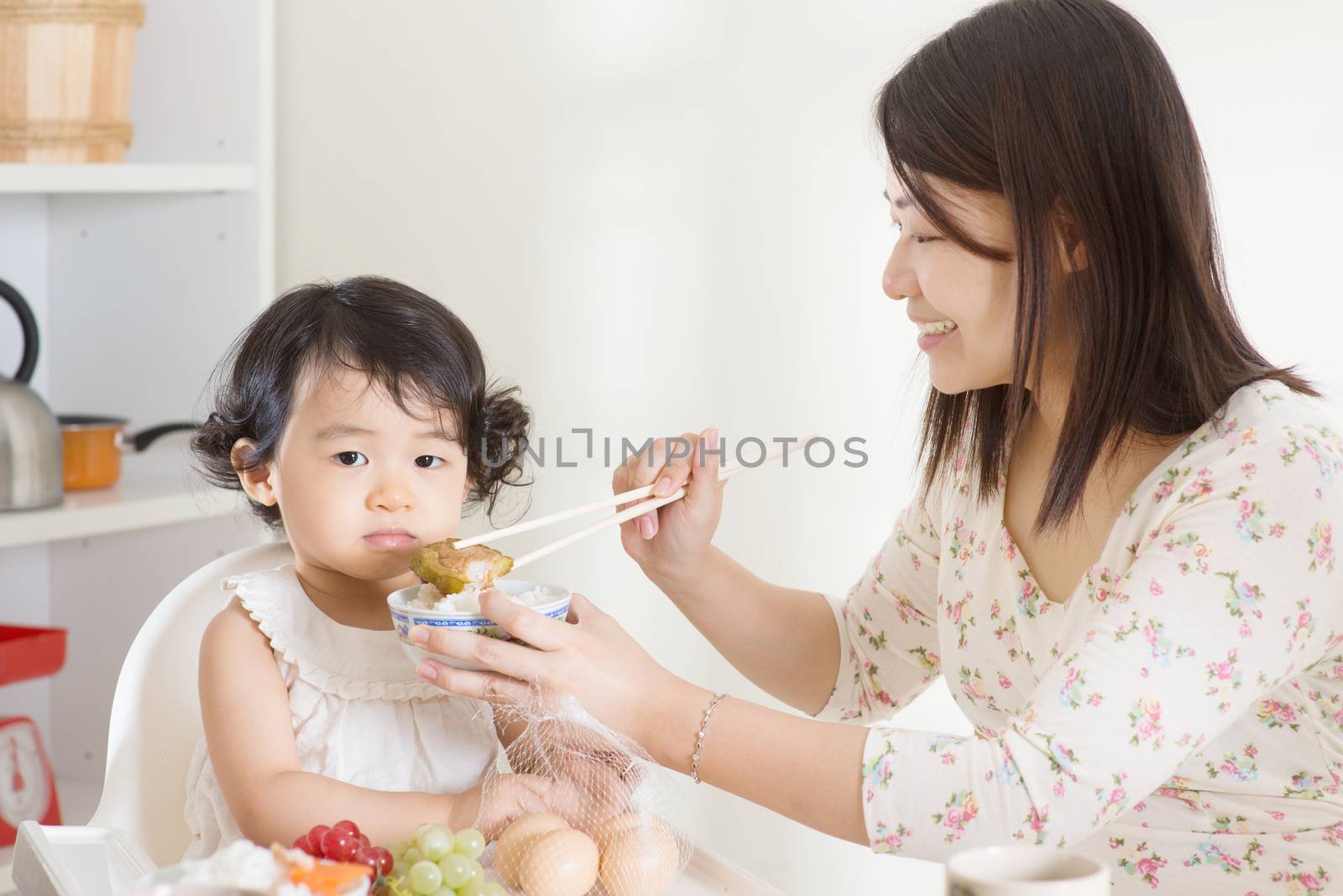 Asian mother feeding her child at home.