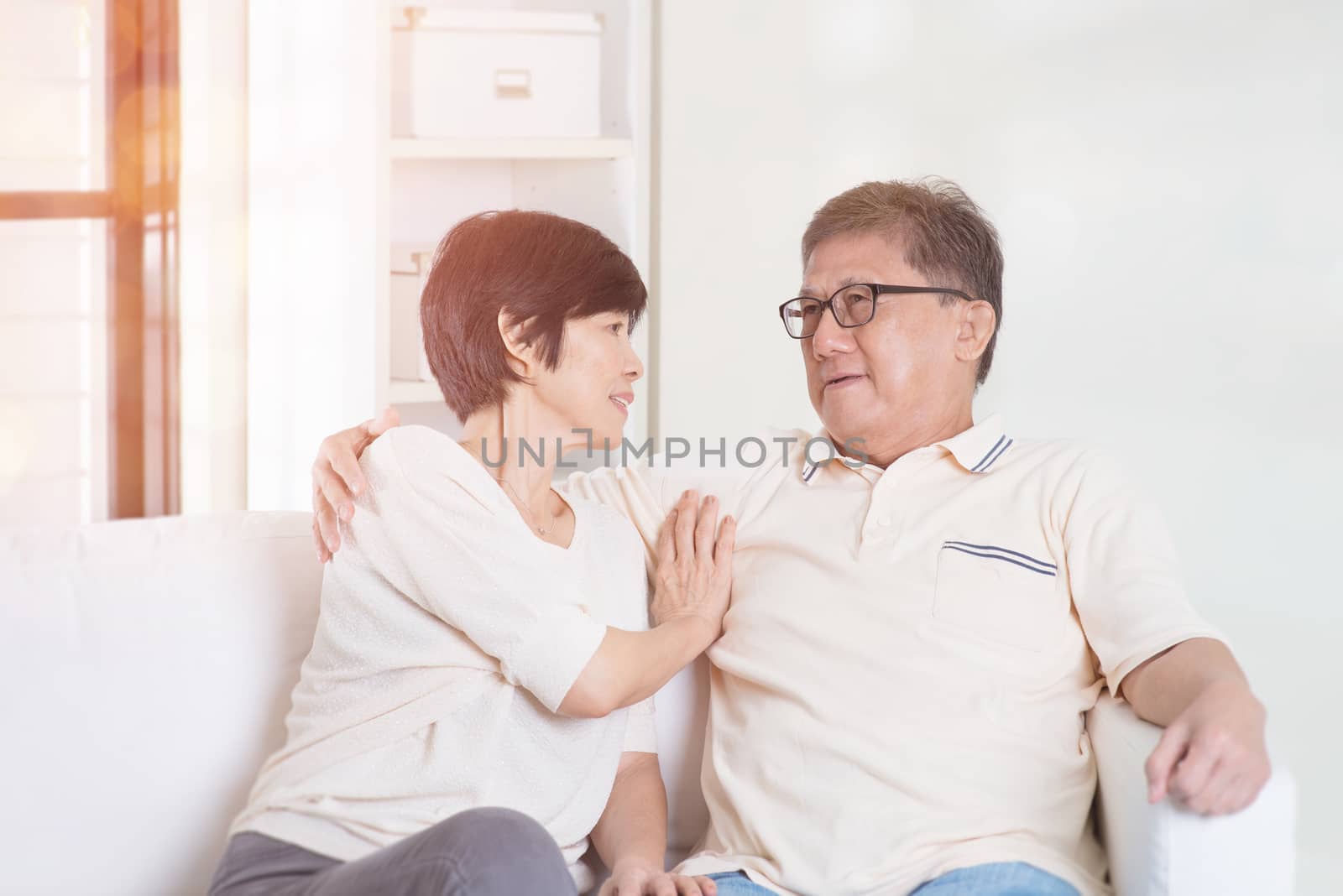 Senior couple chatting, sitting on sofa at home. Living lifestyle of Asian family.