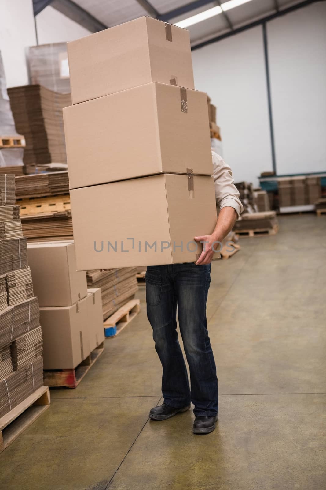 Obscured worker carrying boxes in the warehouse