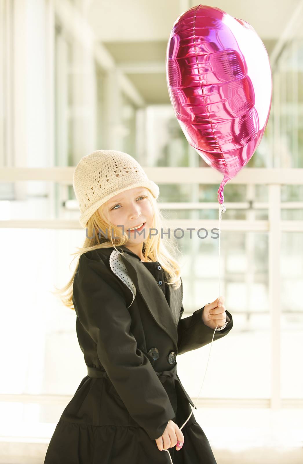 Portrait of a girl in black dress. Charming child with air baloons posing on white background indoors. Studio shot