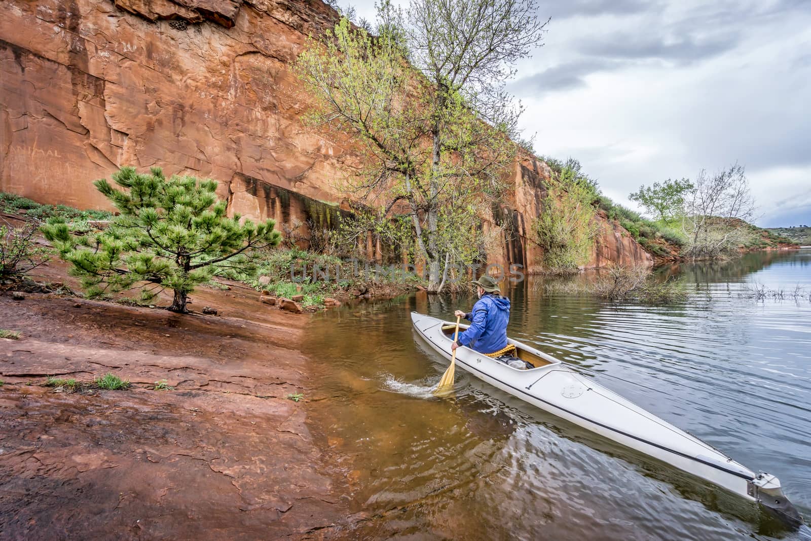 canoe paddler and sandstone cliff by PixelsAway