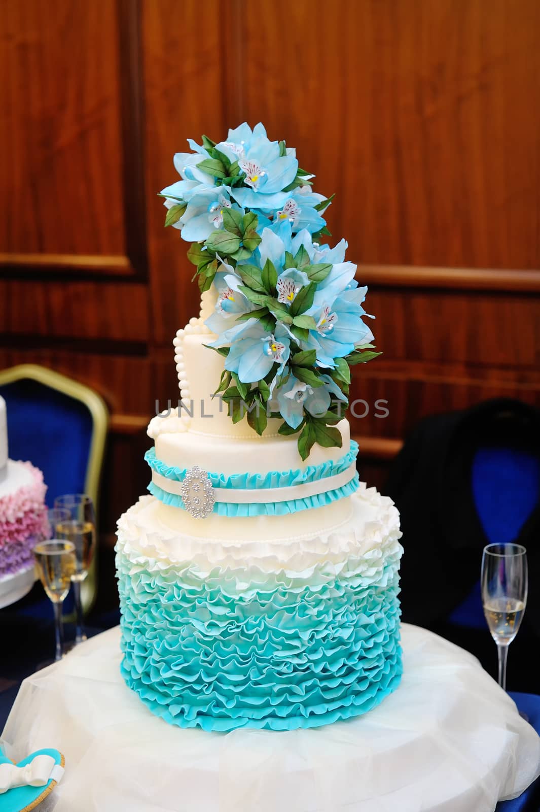 beautiful turquoise three-tiered wedding cake on round table.