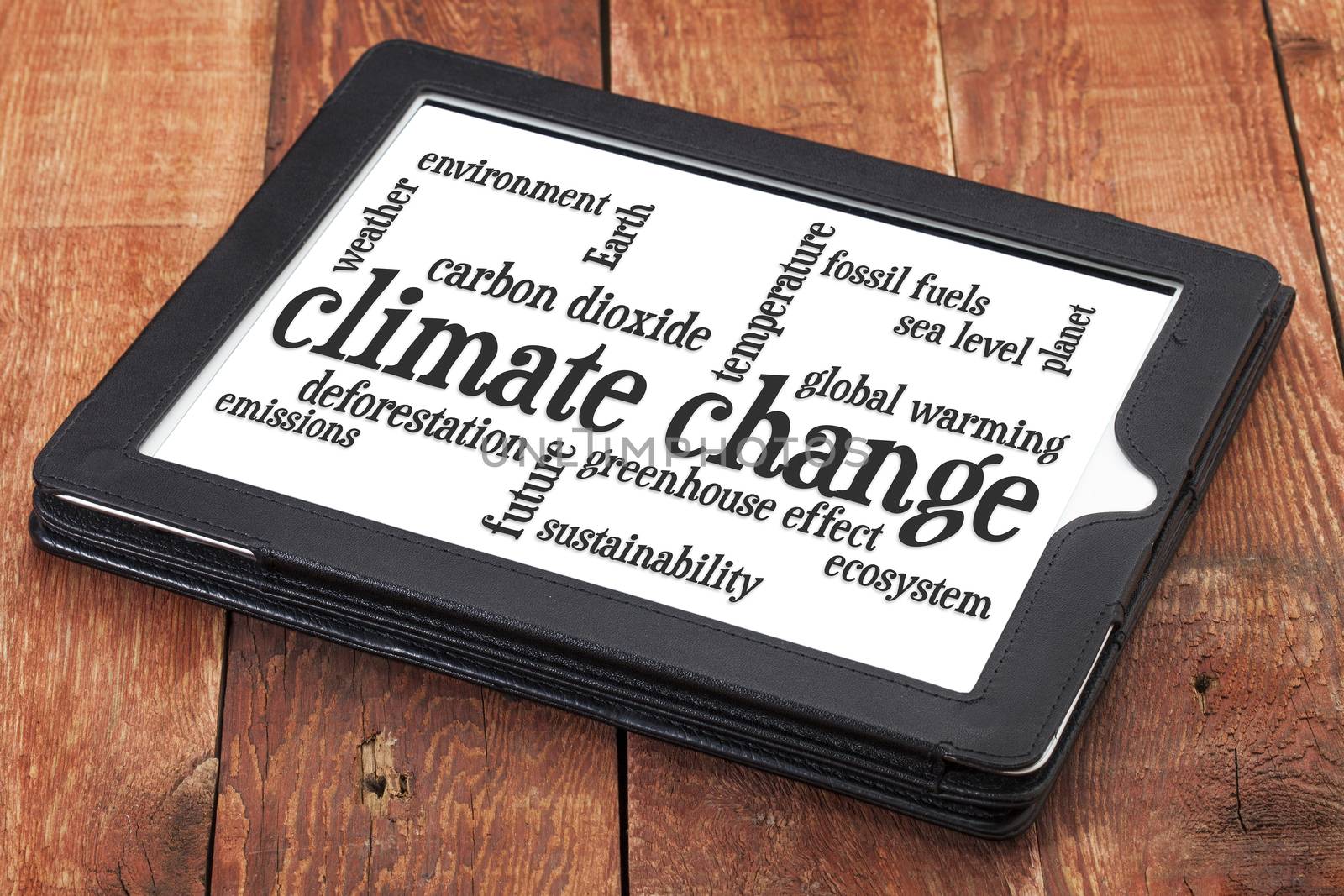 climate change word cloud on a digital tablet against rustic barn wood