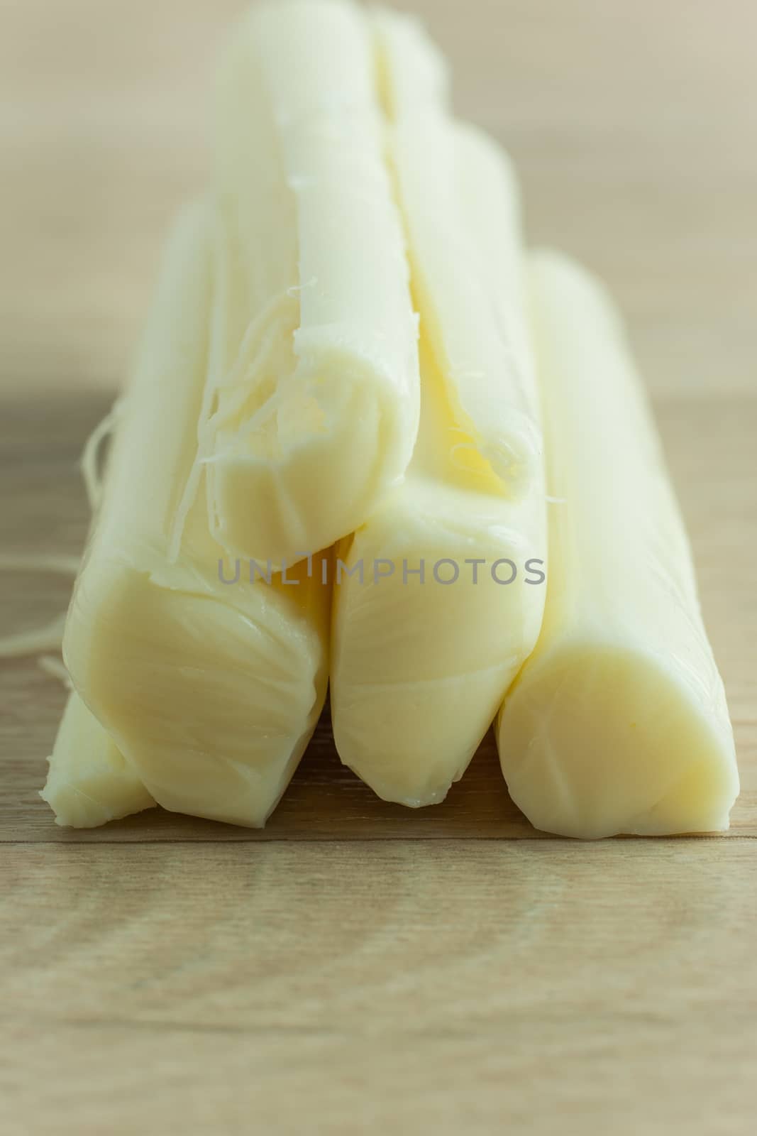 Sticks of mozzerella string cheese on a light colored table top.