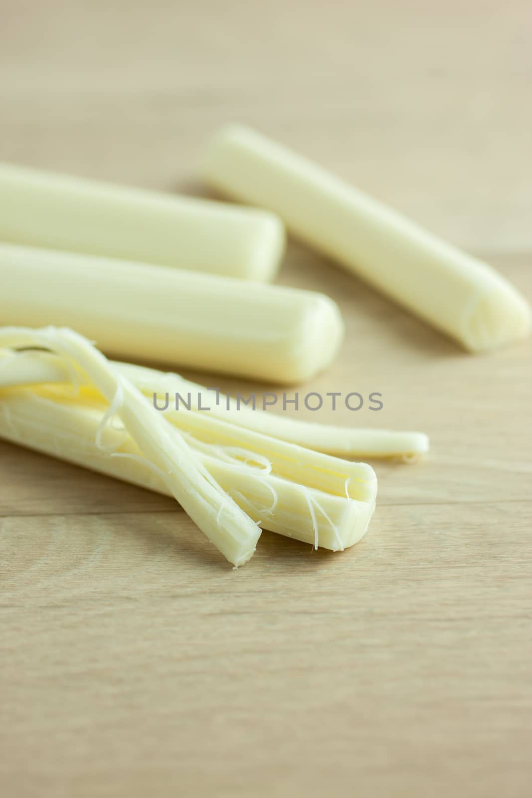 Sticks of mozzerella string cheese on a light colored table top.