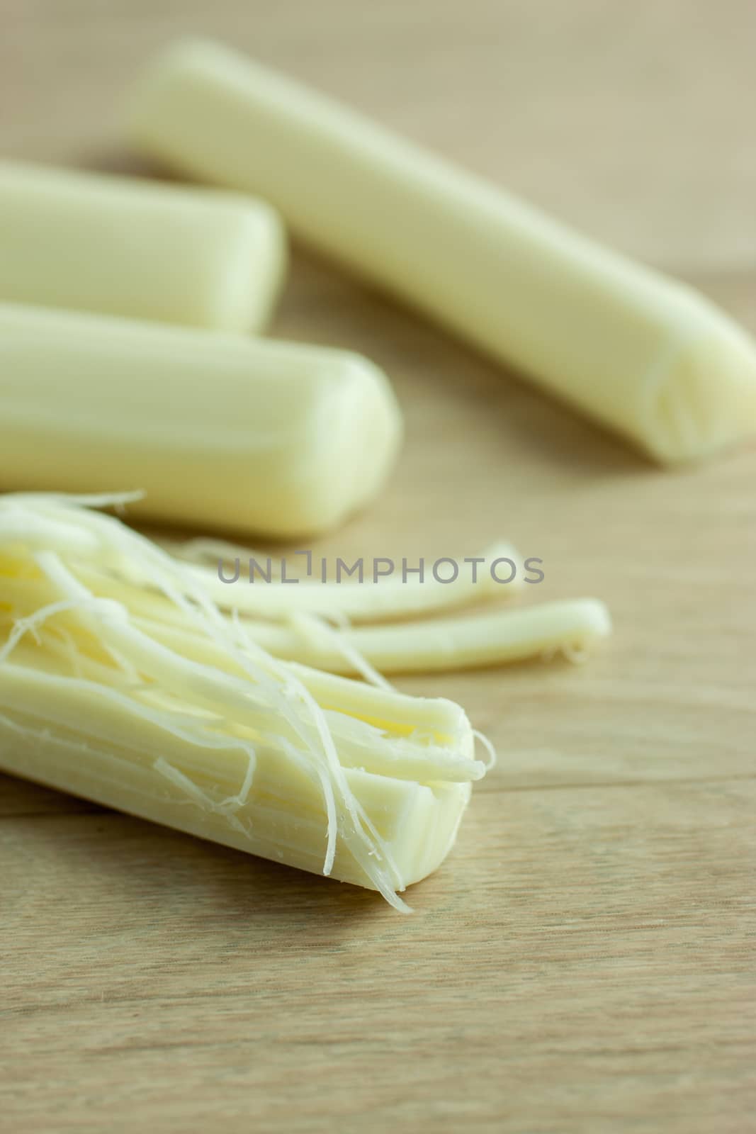 Sticks of mozzerella string cheese on a light colored table top.