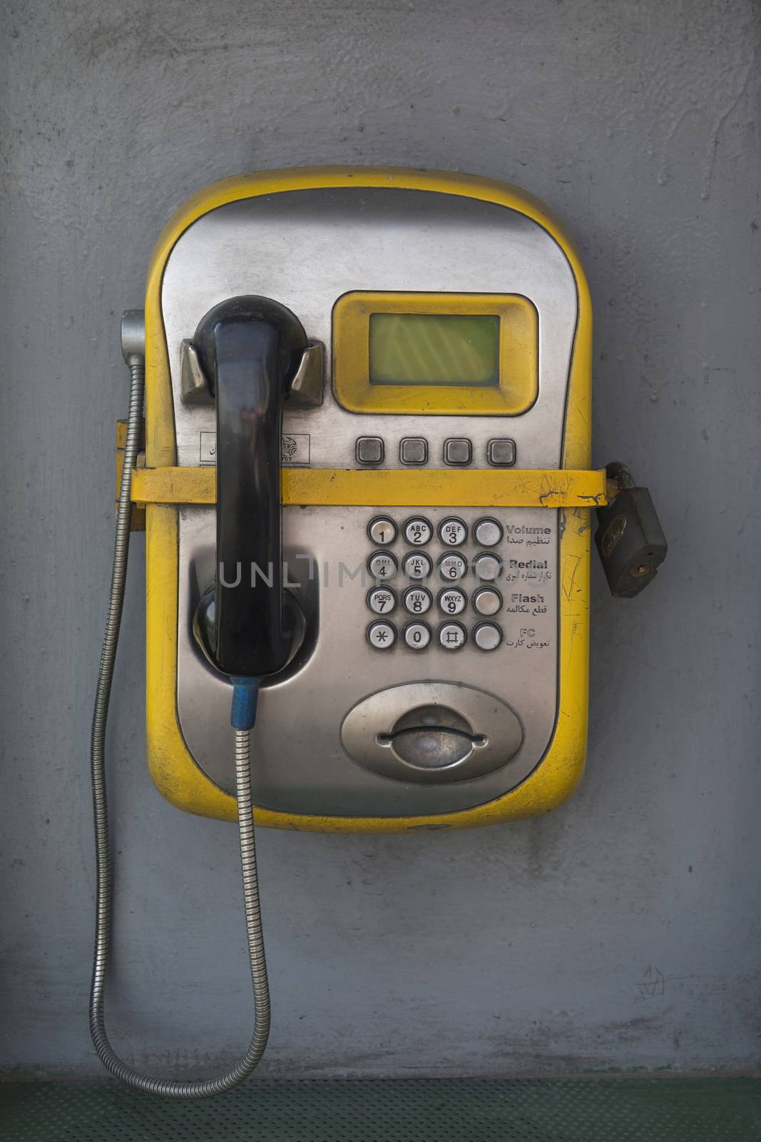 Public phone secured by lock for misusing and rubbery actions.