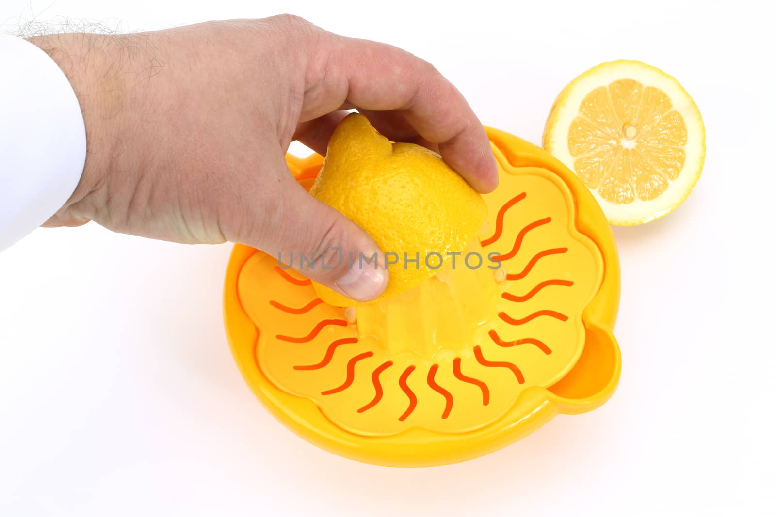 A male hand holding half of an lemon on a squeezer.