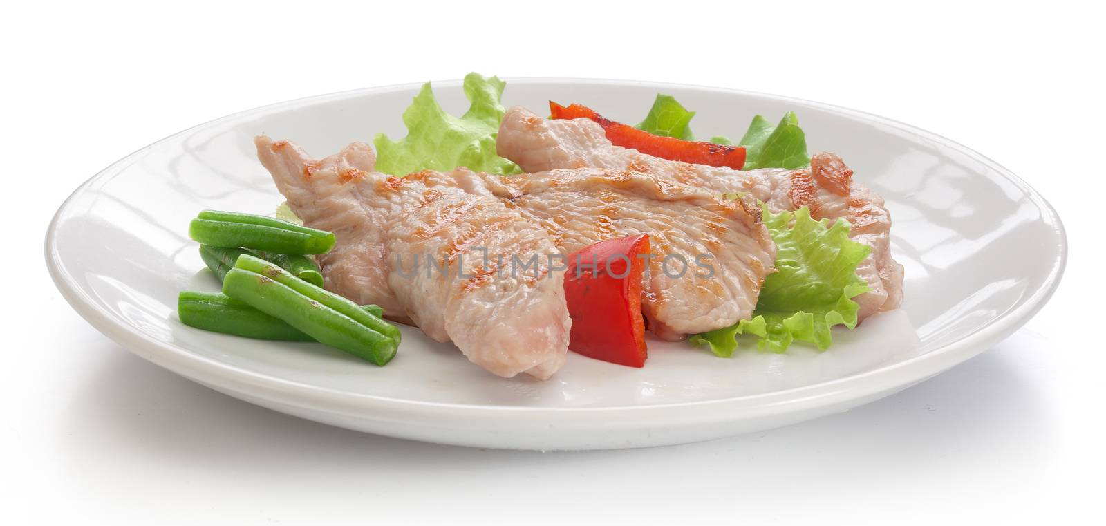 Three roasted pieces of turkey with green lettuce, kidney bean and red pepper on the white plate