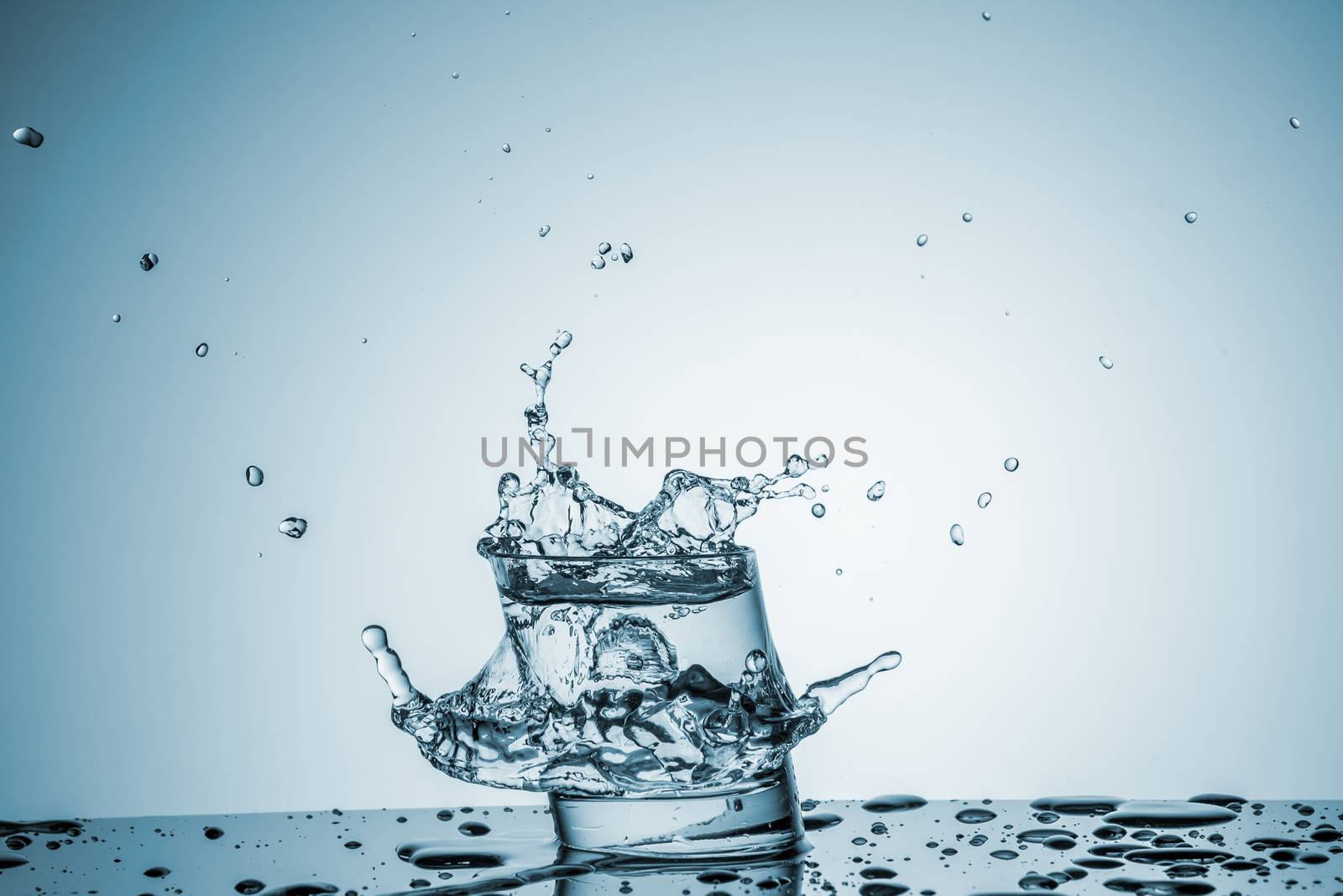 ice cube falling into a glass of water on blue background