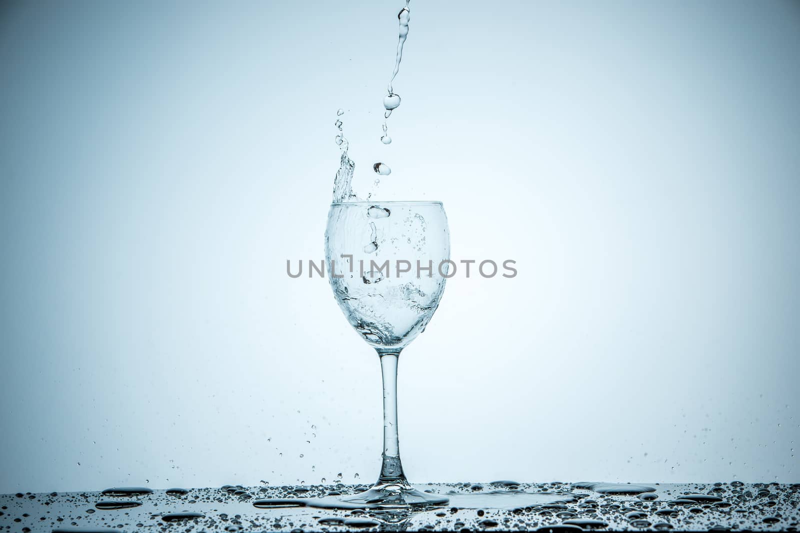 A glass being filled with water on white background