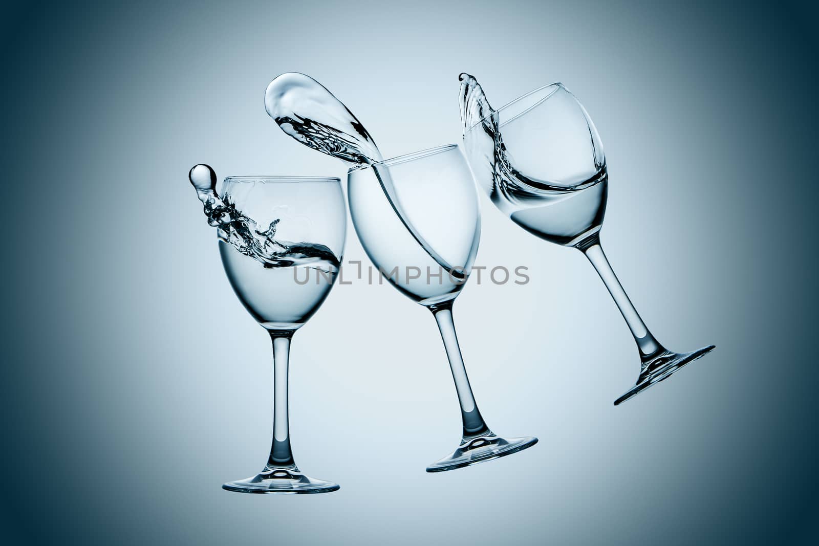 Three water glasses splash on gray background