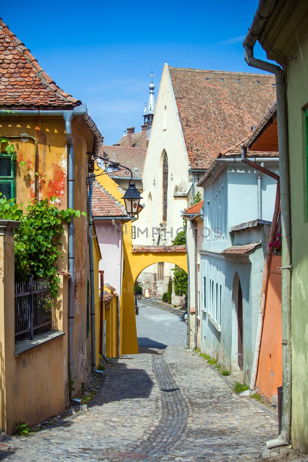 Sighisoara, Romania - June 23, 2013: Old stone paved street with tourists from Sighisoara fortress, Transylvania, Romania