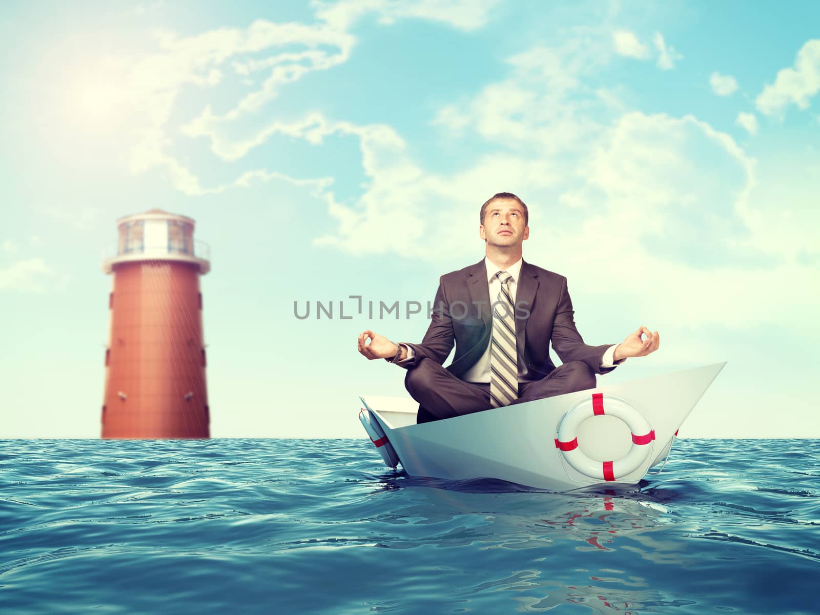 Businessman sitting in lotus position on paper boat and lighthouse in sea and looking up