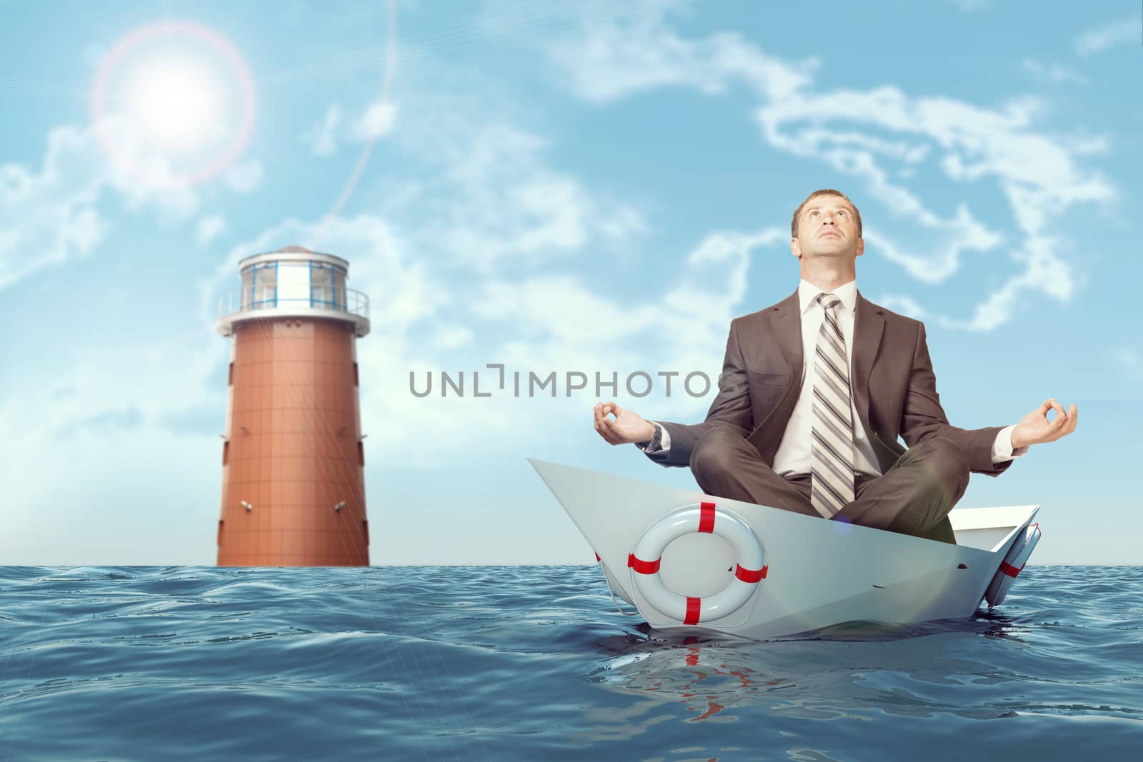 Businessman sitting in lotus position in paper boat and lighthouse in sea and looking up