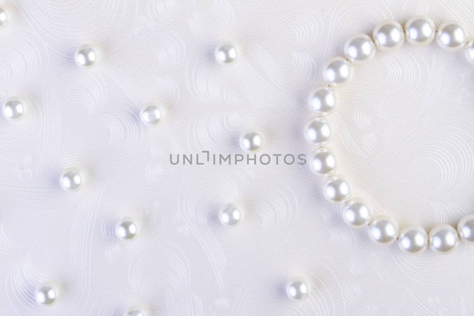 White pearls necklace on white paper  by manaemedia