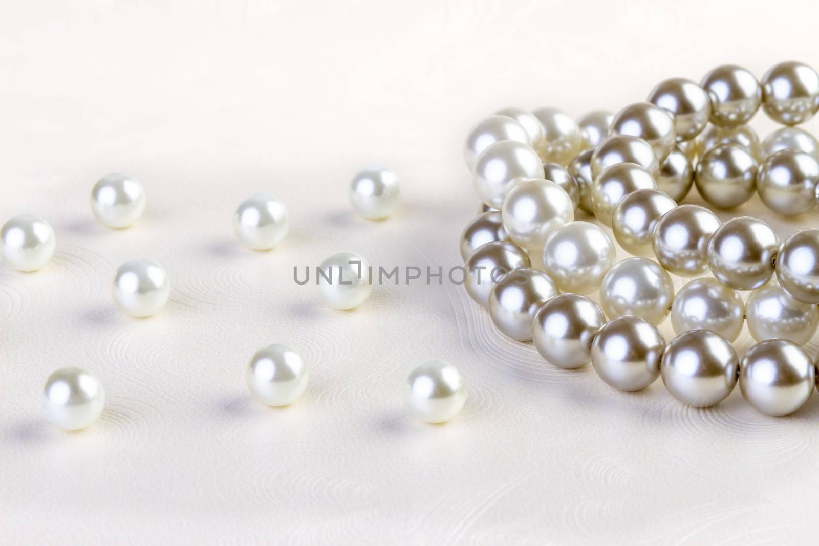 Silver and White pearls necklace on white paper  by manaemedia