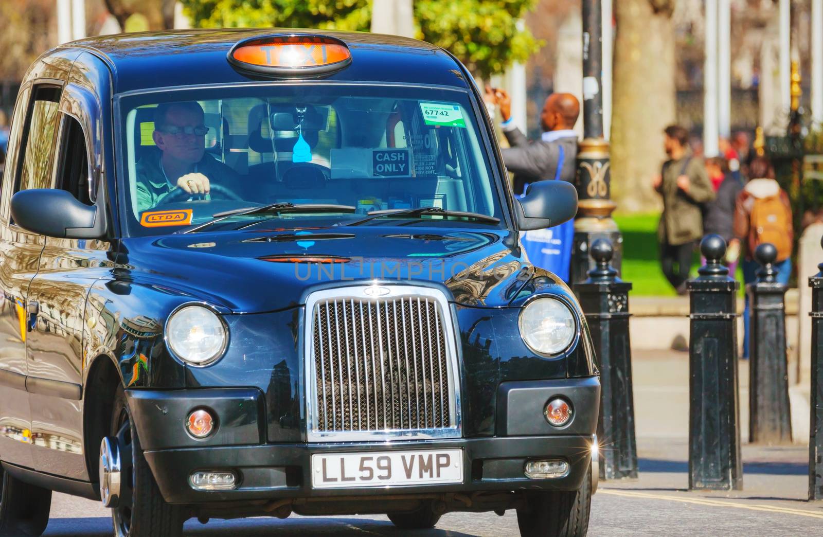 LONDON - APRIL 12: Famous taxi cab (hackney) an a street on April 12, 2015 in London, UK. A hackney or hackney carriage (also called a cab, black cab, hack or London taxi) is a carriage or automobile for hire.