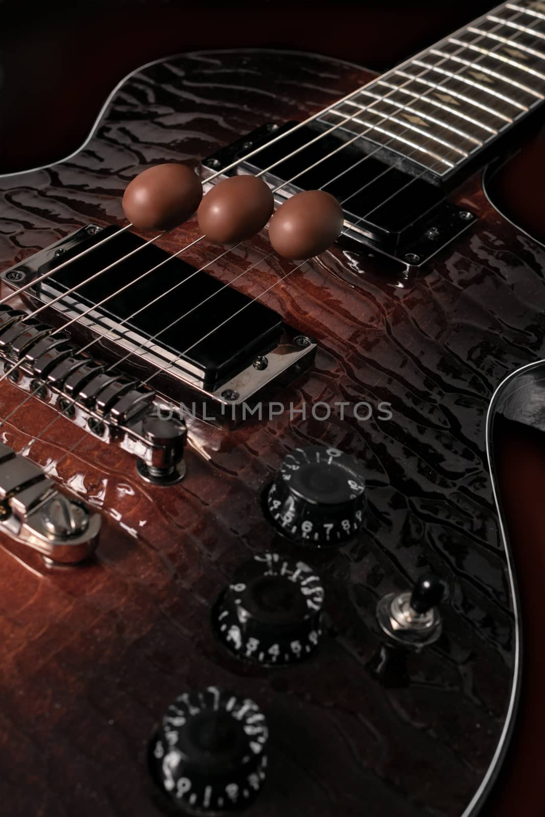 three chocolate eggs placed on the strings of a guitar