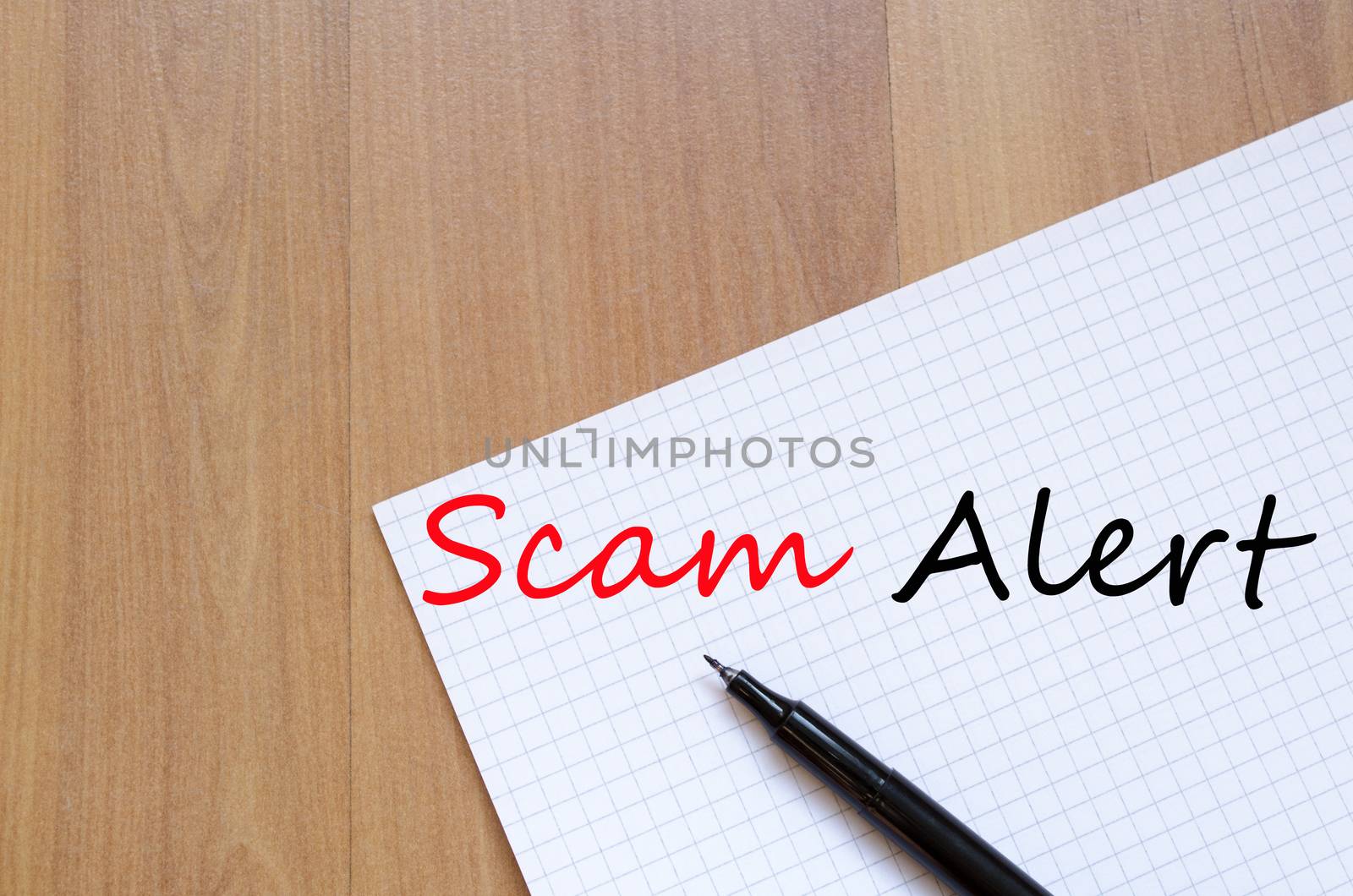 White blank notepad on office wooden table Scam Alert concept