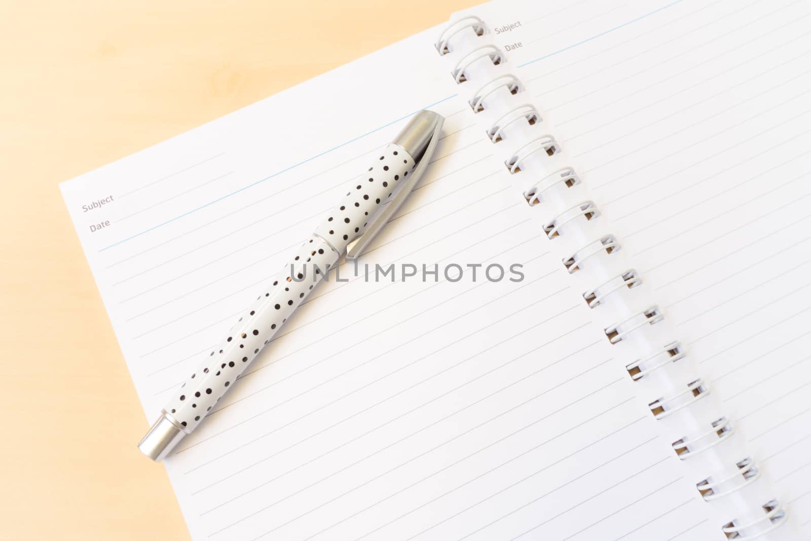 Open White Notebook with Lines and White Dot Pen with Business Concept on Wooden Table