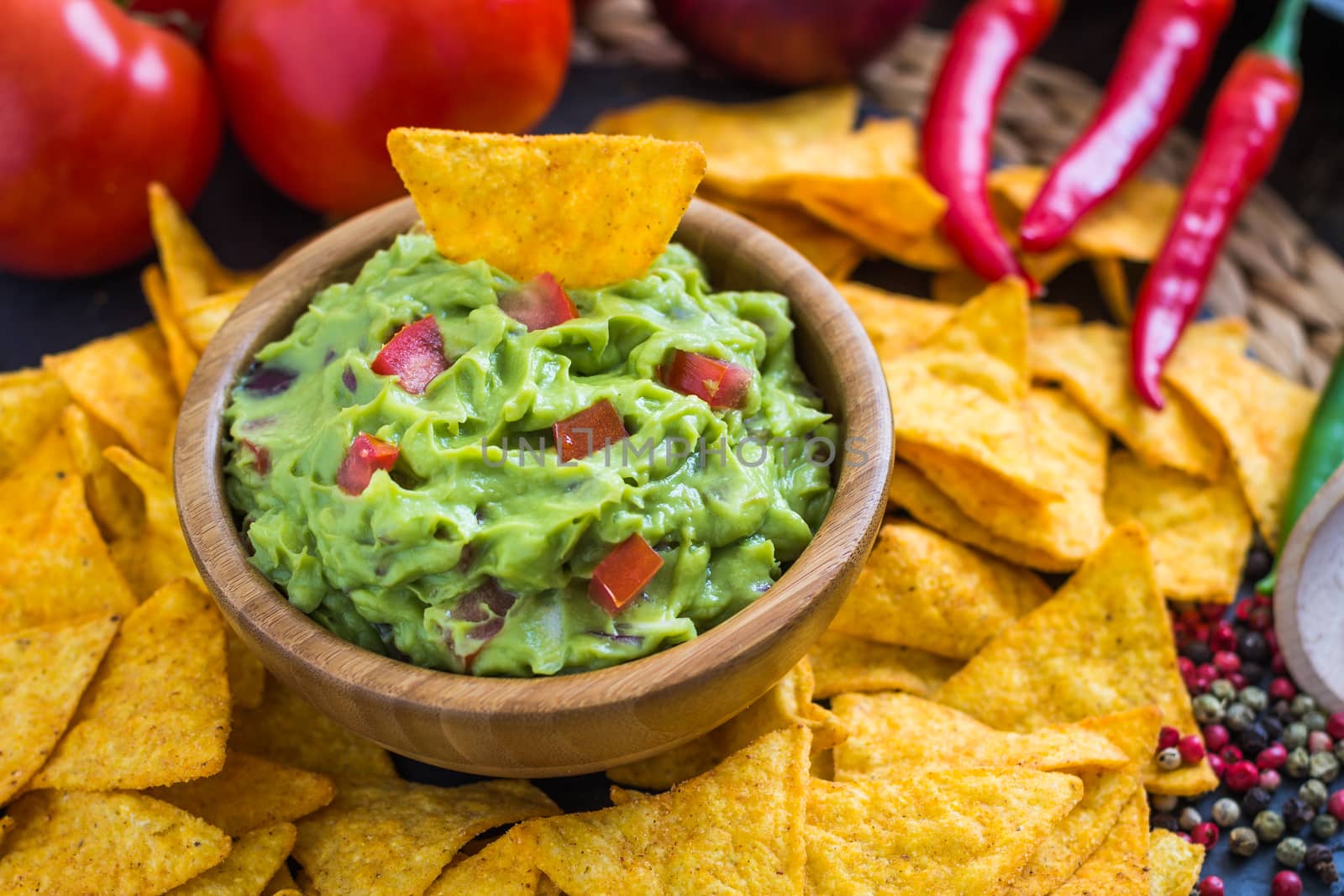 Guacamole in Wooden Bowl with Tortilla Chips and Ingredients