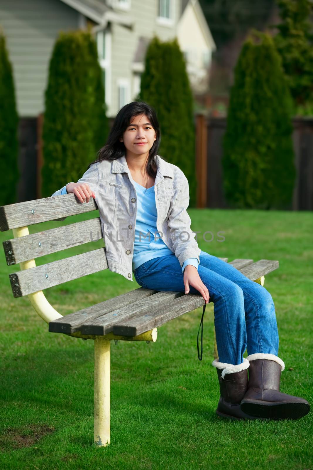Young biracial teen girl enjoying outdoors on park bench