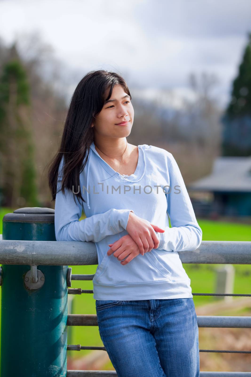 Young teen girl standing, leaning against railing at park by jarenwicklund