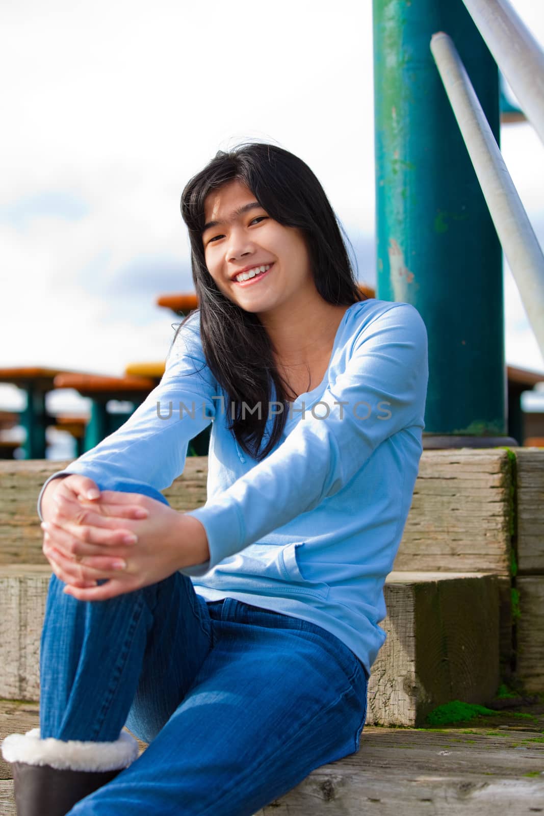 Young teen girl sitting on wooden steps outdoors on overcast clo by jarenwicklund