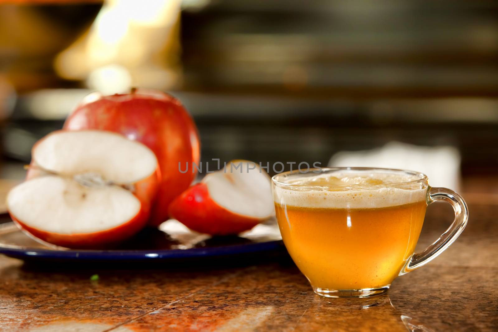 Glass cup of freshly juiced apple on kitchen counter next to plate of raw apples