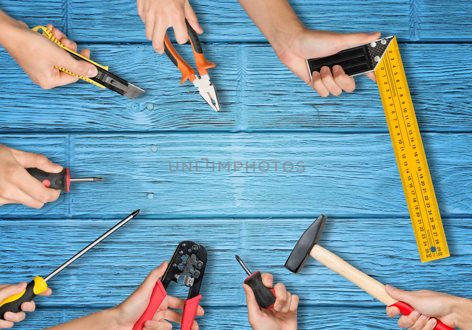 Set of peoples hands holding different tools on blue board texture background