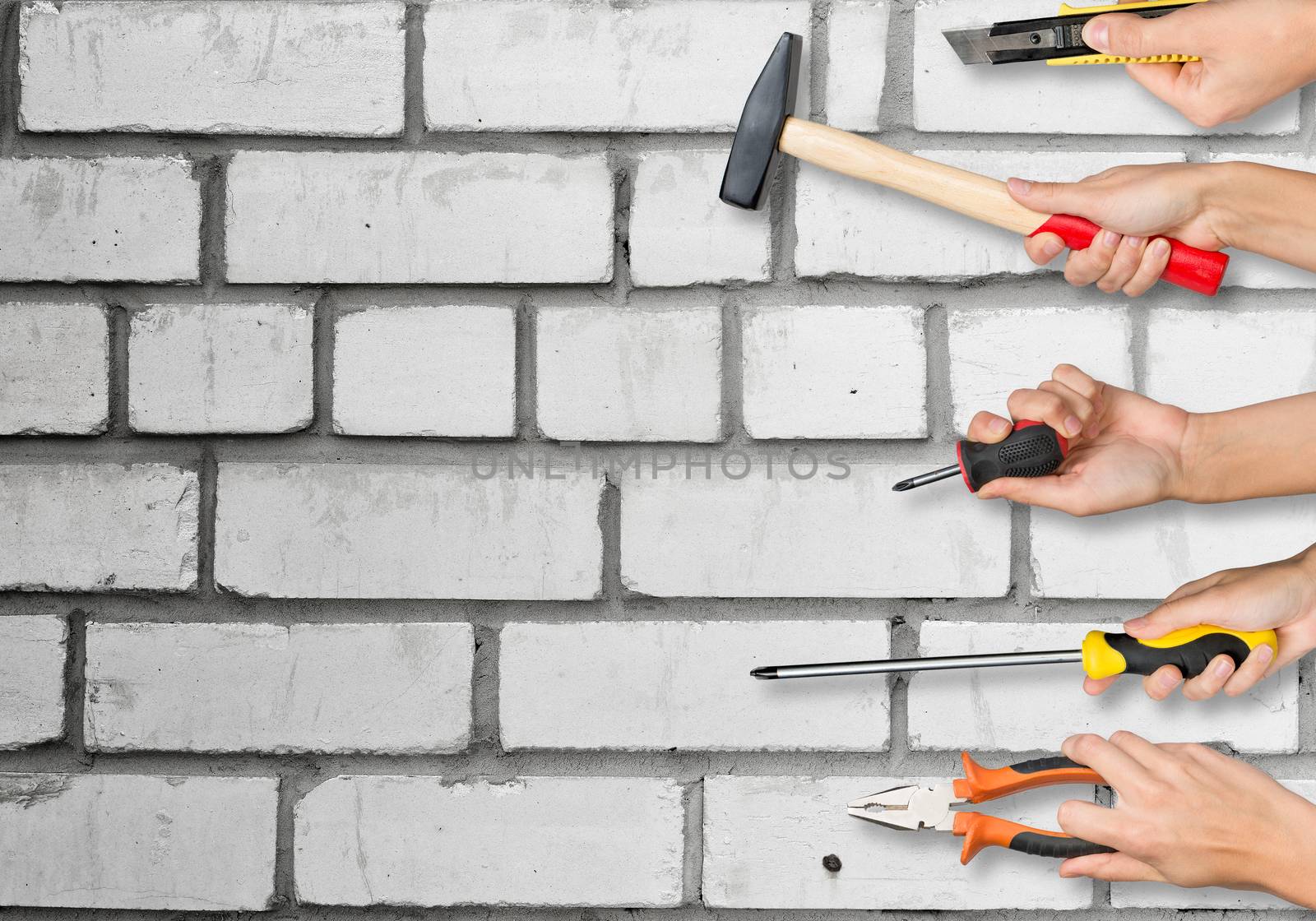 Set of peoples hands holding different tools on white brick wall texture background