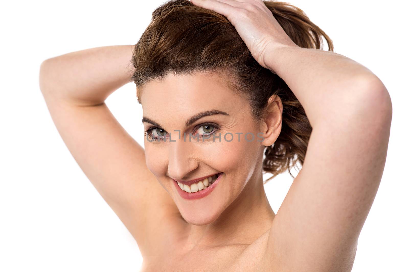 Smiling topless woman tying her hair