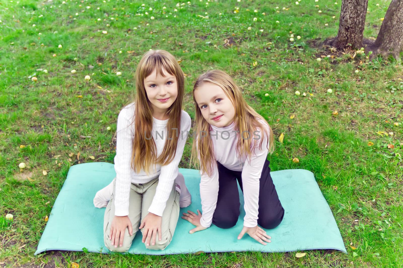 Photo of two girls sitting on grass in summer