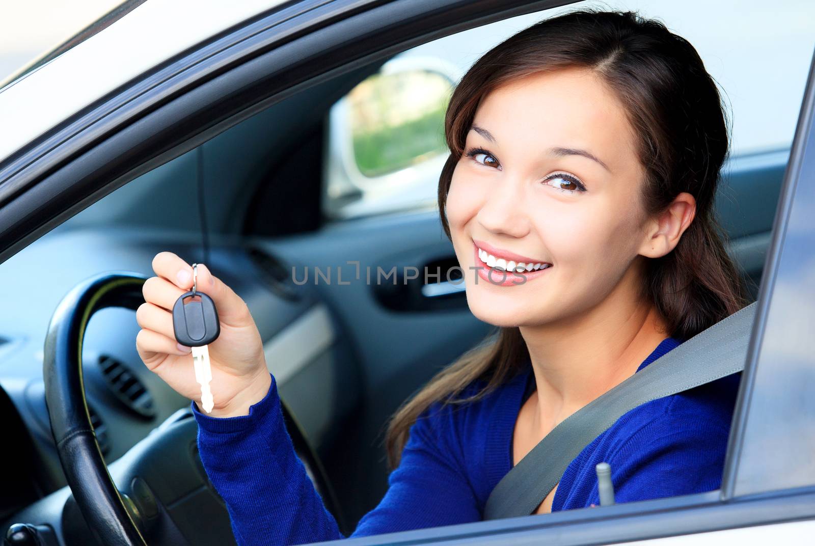 Pretty female driver in a white car showing the car key by Nobilior