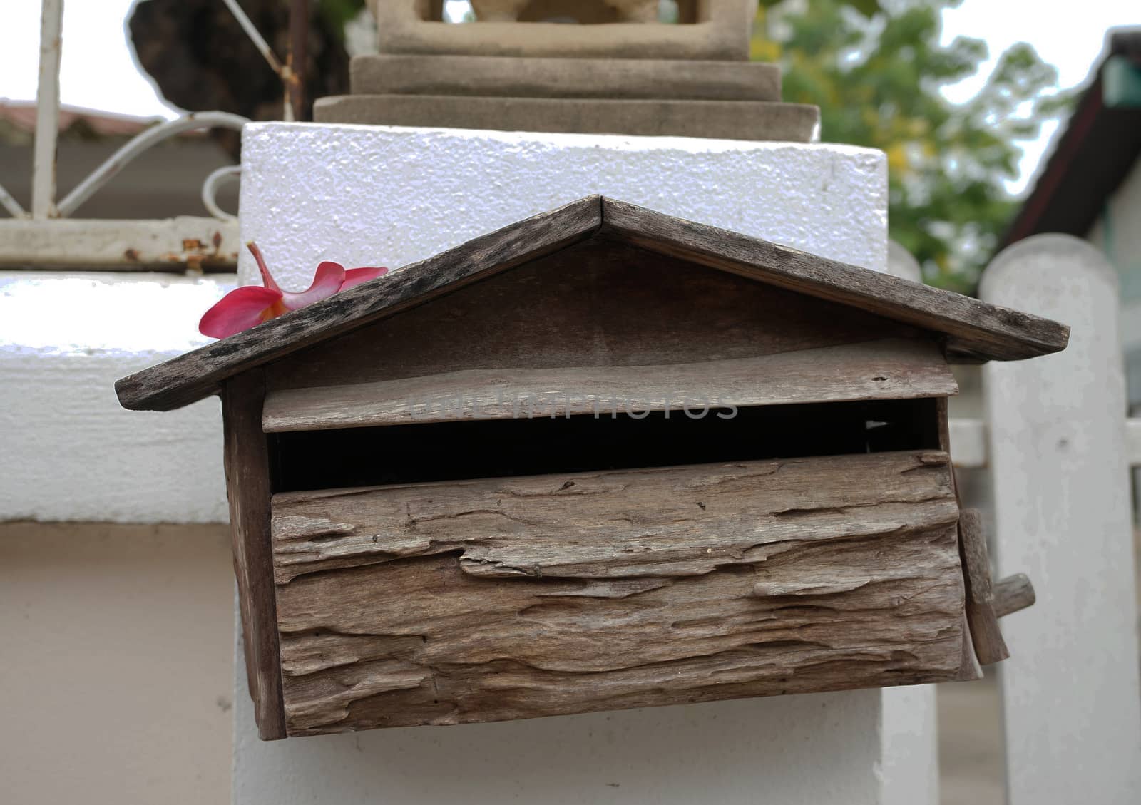 Old wooden mailbox, house shape placed on white wall background.                            