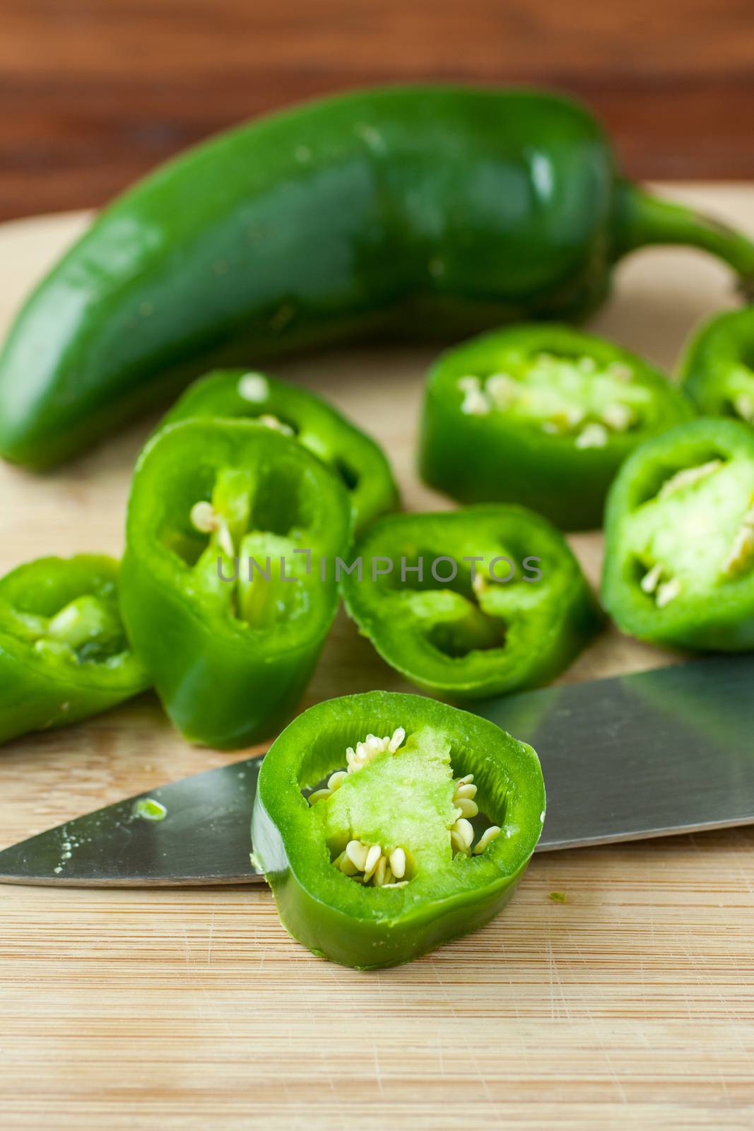 Sliced jalapeno peppers on a bamboo cutting board.
